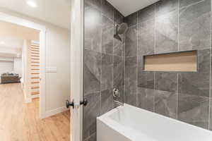 Bathroom with recessed lighting, tiled shower / bathing tub combination, baseboards, and wood finished floors