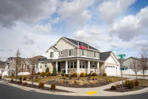 View of front of property with an attached garage, covered porch, stone siding, driveway, and board and batten siding