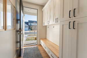 Mudroom featuring light wood-style flooring, custom cabinetry, and exterior door.