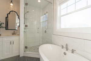 Owner’s Bathroom with a wealth of natural light, a freestanding bath, a beautifully tiled shower with double shower heads and glass doorl, and vanity