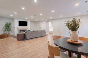 Living room with recessed lighting, light wood-style flooring, visible vents, and a cozy glass covered fireplace