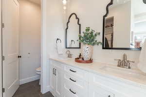 Owner’s full bath with toilet, tile patterned flooring, double vanity, and a sink