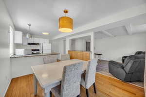 Dining space featuring beamed ceiling, light wood-type flooring, and baseboards