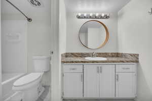 Bathroom featuring toilet, baseboards, vanity, and shower / washtub combination