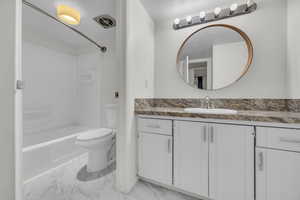 Full bath featuring toilet, tub / shower combination, marble finish floor, and vanity