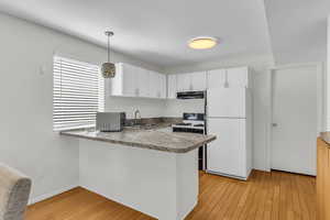 Kitchen featuring a sink, a peninsula, stainless steel microwave, freestanding refrigerator, and under cabinet range hood