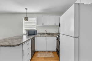 Kitchen featuring freestanding refrigerator, stainless steel dishwasher, white cabinetry, and a sink