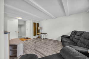 Living area with beam ceiling and light wood-style flooring