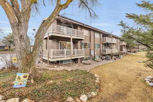 Rear view of house with central AC, brick siding, and a balcony