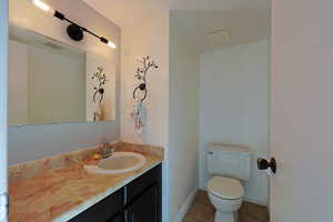 Bathroom with visible vents, toilet, vanity, baseboards, and tile patterned floors