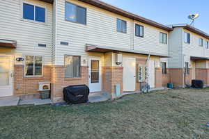 Rear view of property with brick siding and a lawn