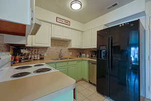 Kitchen featuring visible vents, dishwasher, black refrigerator with ice dispenser, white electric range, and a sink