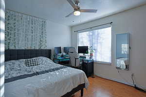 Bedroom featuring a textured ceiling, wood finished floors, a ceiling fan, and baseboards