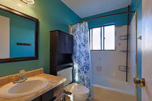 Full bathroom featuring shower / tub combo with curtain, vanity, and toilet