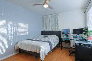 Bedroom featuring ceiling fan, wood finished floors, and baseboards