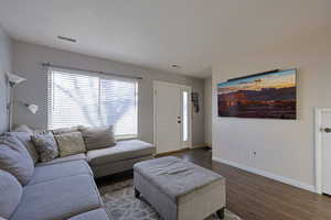 Living area featuring visible vents, dark wood finished floors, and baseboards