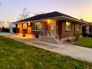 Single story home with concrete driveway, brick siding, an outdoor structure, and a lawn