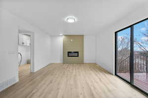 Unfurnished living room with light wood finished floors, a fireplace, and baseboards