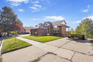 View of front of house with a garage, concrete driveway, a front lawn, and brick siding