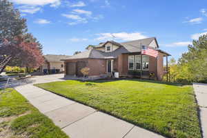 View of front of home with a garage, brick siding, concrete driveway, roof with shingles, and a front lawn