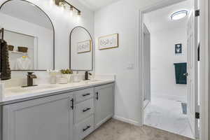 Bathroom featuring double vanity, marble finish floor, baseboards, and a sink