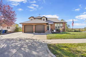 View of front facade with an attached garage, brick siding, a shingled roof, concrete driveway, and a front yard