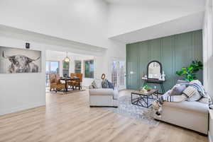 Living area featuring high vaulted ceiling, french doors, baseboards, and wood finished floors