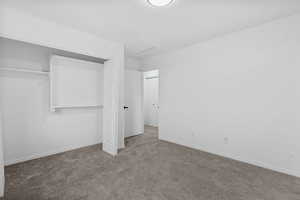 Unfurnished bedroom with attic access, a closet, baseboards, and carpet flooring