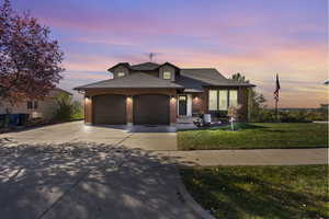 View of front facade featuring a garage, a shingled roof, concrete driveway, a yard, and brick siding