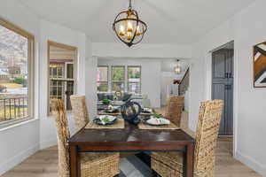 Dining room featuring stairs, light wood finished floors, baseboards, and a notable chandelier