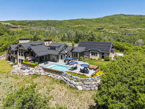 Back of property featuring stone siding, a standing seam roof, outdoor dining space, a chimney, and a patio area