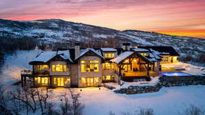 Snow covered house featuring a balcony, a chimney, a mountain view, and a patio