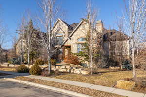 French country inspired facade featuring stone siding, a mountain view, and roof with shingles