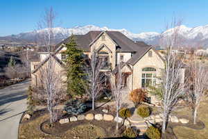 French country inspired facade featuring stone siding, a mountain view, and roof with shingles