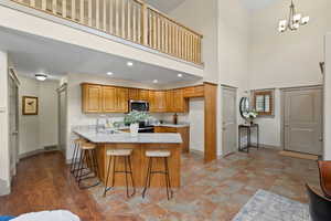Kitchen featuring light stone counters, visible vents, stainless steel microwave, a sink, and a peninsula