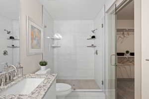 Full bathroom with toilet, a shower stall, a walk in closet, and vanity