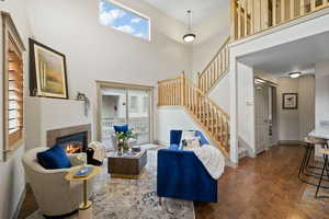Living room featuring a fireplace, stairway, a high ceiling, wood finished floors, and baseboards