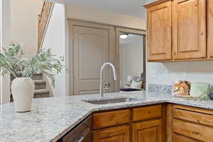 Kitchen featuring light stone counters, a sink, and dishwasher