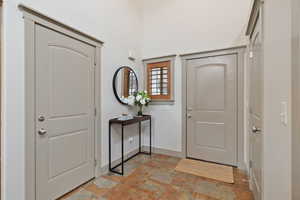 Foyer entrance with stone finish floor and baseboards
