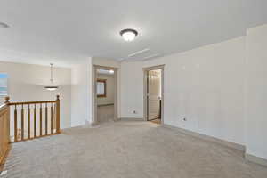 Spare room featuring baseboards, attic access, and light colored carpet