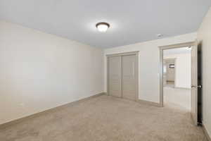 Unfurnished bedroom featuring light carpet, baseboards, and a closet