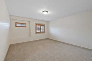 Carpeted spare room featuring a textured ceiling and baseboards