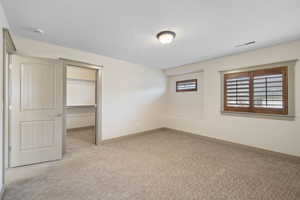 Unfurnished bedroom with carpet flooring, visible vents, baseboards, a closet, and a walk in closet