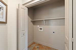 Clothes washing area with washer hookup, stone finish floor, electric dryer hookup, laundry area, and baseboards