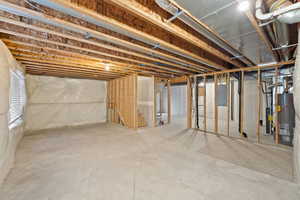 Unfinished below grade area with electric panel and water heater
