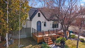 English style home with brick siding, roof with shingles, stairway, fence, and a deck