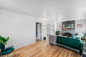 Living room with baseboards, arched walkways, visible vents, light wood-style floors, and a fireplace