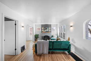 Living area with arched walkways, a fireplace, visible vents, baseboards, and light wood-type flooring