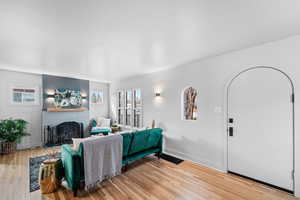 Living room with baseboards, a brick fireplace, and light wood-style floors