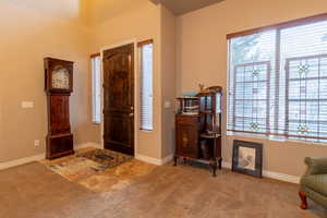 Carpeted foyer entrance with baseboards and a wealth of natural light